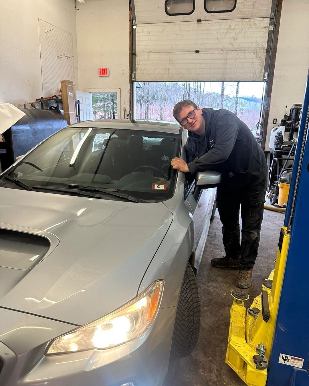 A member of the NH Mobile Mechanics team beside a car in the garage